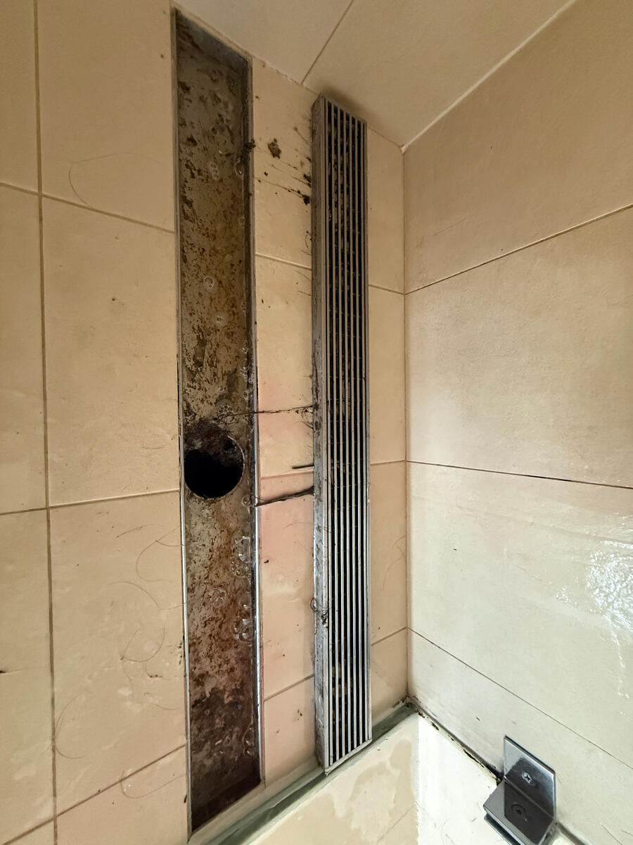 Shower drain channel with biofilm buildup — before deep clean